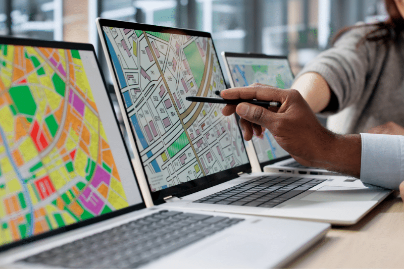 Professionals reviewing digital mapping and land development data on computer screens as part of municipal planning and infrastructure decision-making